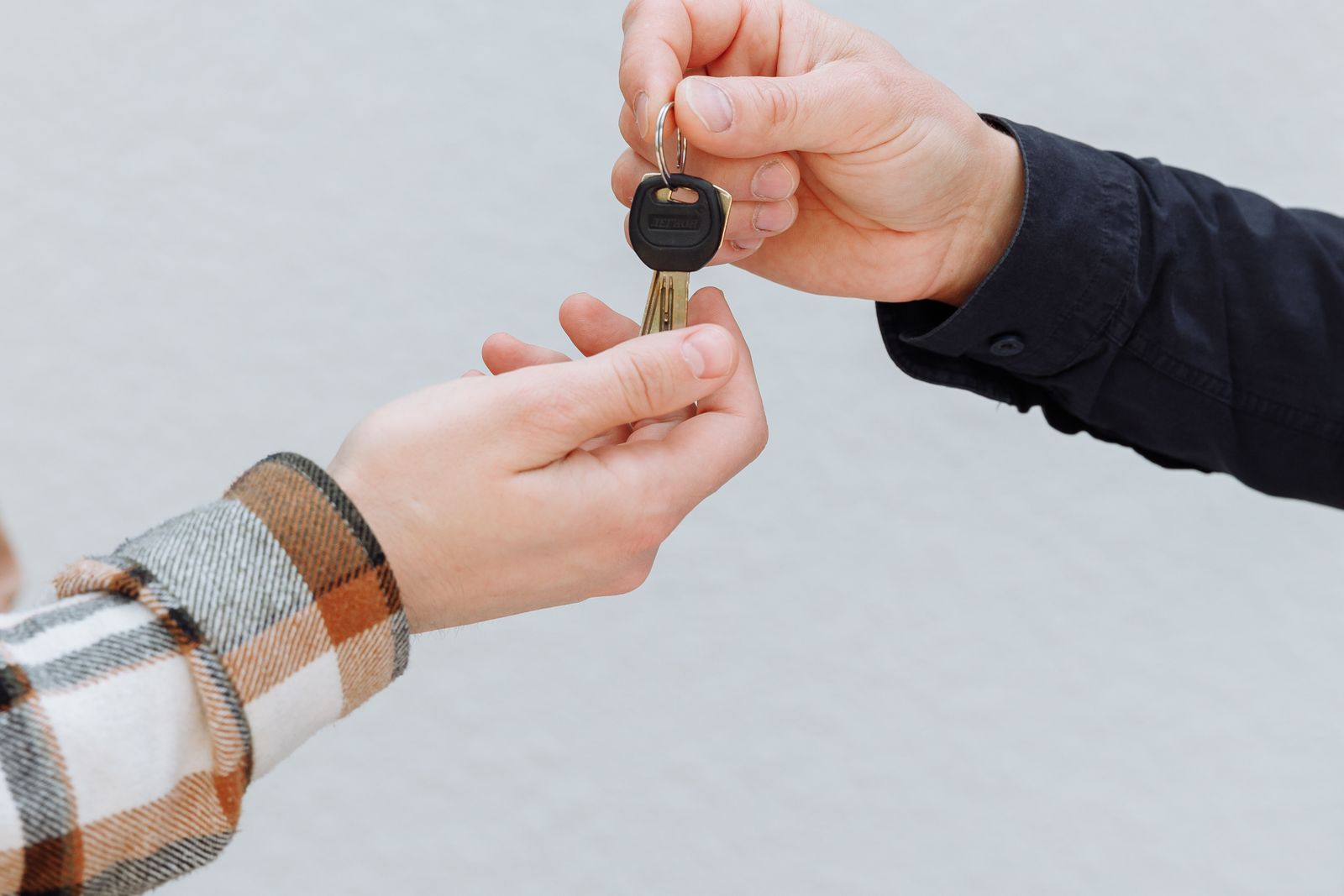 Hands exchanging a car key during a vehicle purchase negotiation