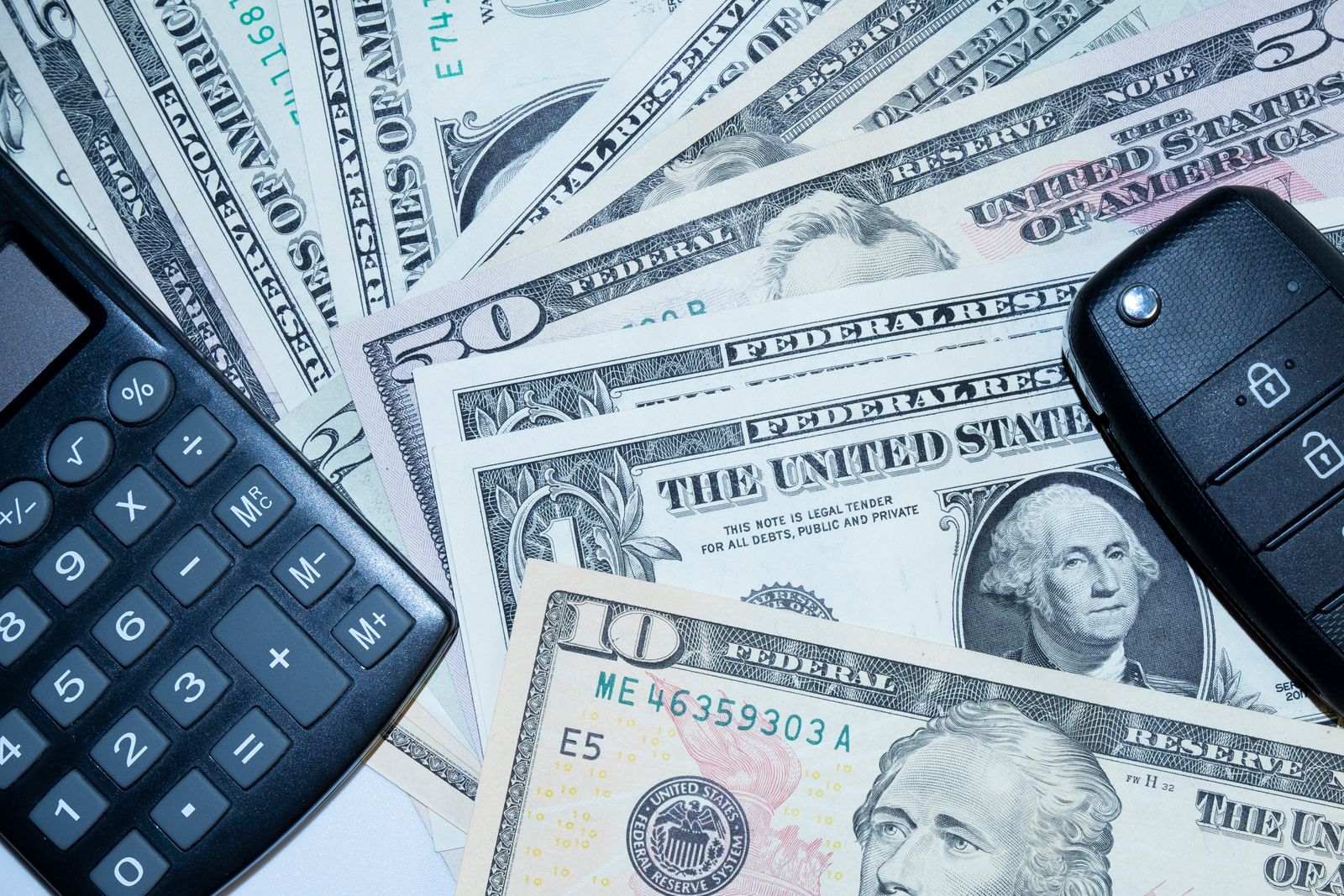 Car keys, a calculator and cash arranged to represent vehicle ownership costs